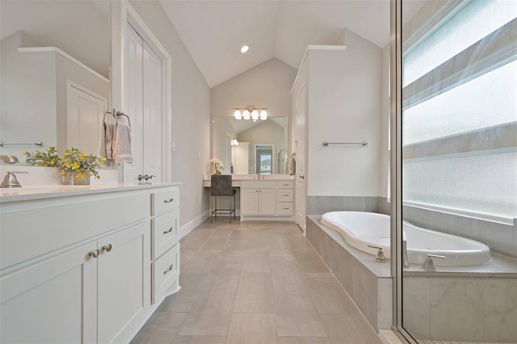 En-suite spa-like primary bathroom, designed with relaxation in mind. It features separate vanities with venetian marble countertops, double sinks, vanity knee space, and stylish vanity lights. The double doors on the left open to an expansive walk-in closet includes a full-length mirror and built-in dresser, providing ample storage and organization. Separate water closet.