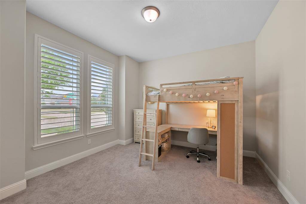 Secondary Bedroom #1 features cozy low-profile carpet and a window adorned with added plantation shutters, allowing for plenty of natural light. The room includes a light fixture and a double door closet for convenient storage. It shares a hollywood bathroom with Secondary Bedroom #2, making it perfect for family or guests.