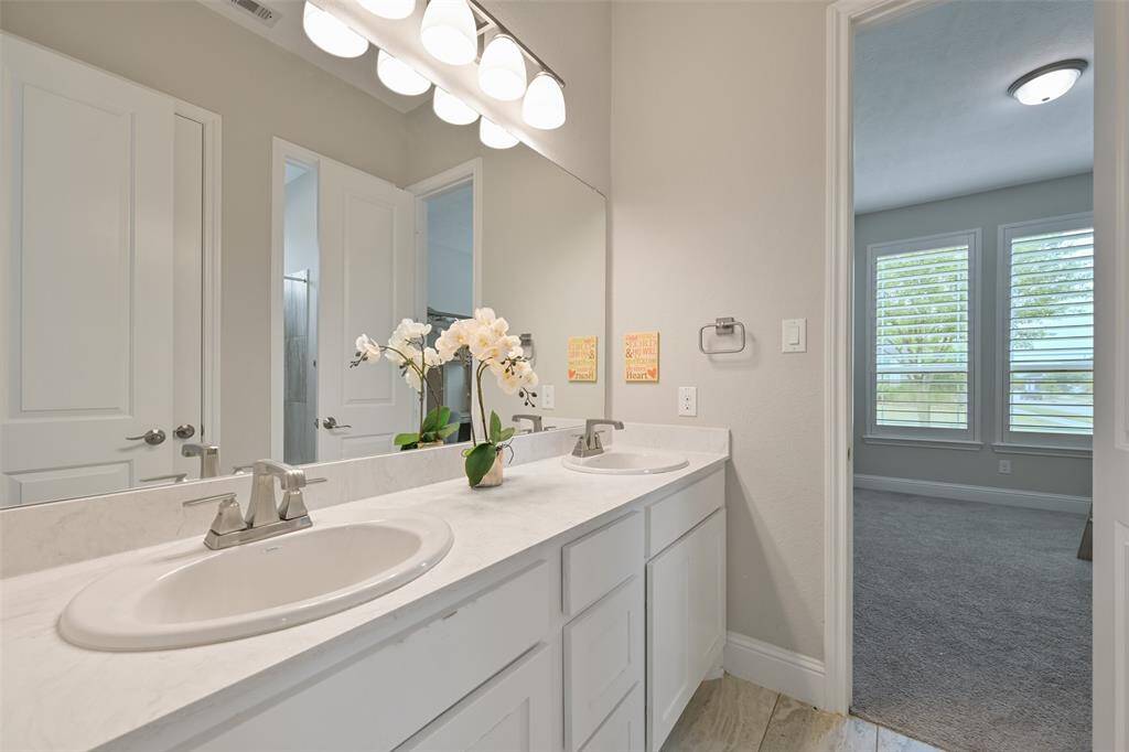 The shared guest bath for Secondary Bedrooms #1 & #2 is designed for convenience with dual sinks and a vanity featuring a luxurious Venetian marble countertop and plenty of storage. The layout includes a separate area with a toilet and a tub/shower combo, ensuring privacy and functionality for both bedrooms.