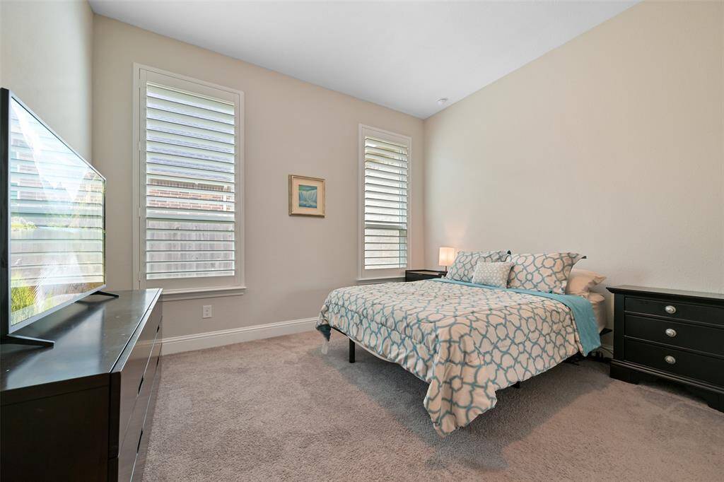 Secondary Bedroom #3 features low-profile carpet, a window with added plantation shutters, and a light fixture that enhances the space. It offers a peaceful retreat with plenty of natural light, storage options and private en-suite bathroom.