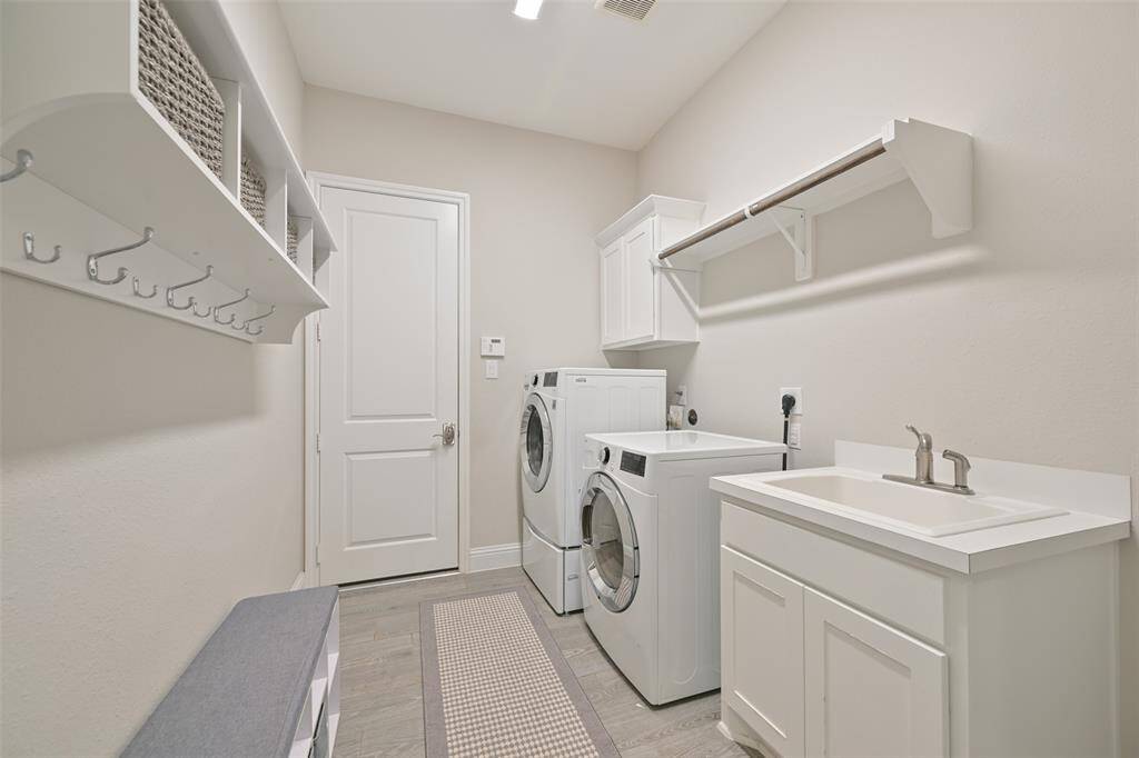 The utility room/mud room is designed for both convenience and functionality, featuring washer and dryer connections, along with a utility sink for added practicality. Storage cabinets provide space for organization. The door leads to the garage, keeping everything neat and easily accessible.