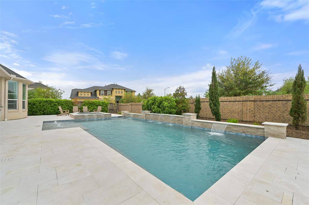 The sizable saltwater heated pool, added in 2021, is the centerpiece of the backyard. It features a stunning waterfall feature and an expansive sun deck with a built-in umbrella holder, providing a perfect spot to relax and enjoy the sun. A built-in hot tub completes the ultimate poolside retreat. The marble tile patio stays cool during summer months.