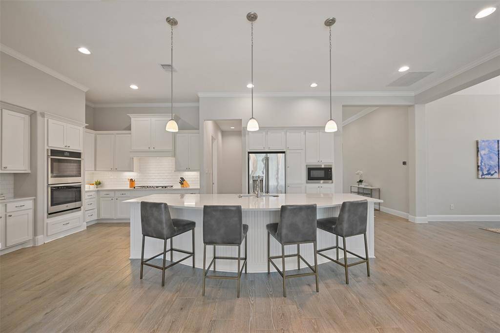 This sizable chef’s kitchen is a dream for both everyday cooking and entertaining. Features stunning silestone countertops paired with a classic white subway tile backsplash. An expansive island with three pendant lights offers both prep space and breakfast bar seating, making it ideal for casual meals or gathering with loved ones. The kitchen is finished with crown molding, under-cabinet lighting, and recessed can lighting, enhancing both function and style.