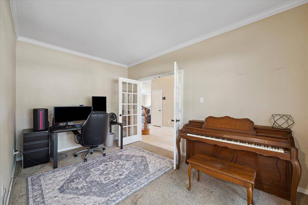 This spacious kitchen features warm wood cabinetry, a central island, and modern appliances. It has tile flooring, ample counter space, and a bright, open layout with natural light from a large window. Gas stove