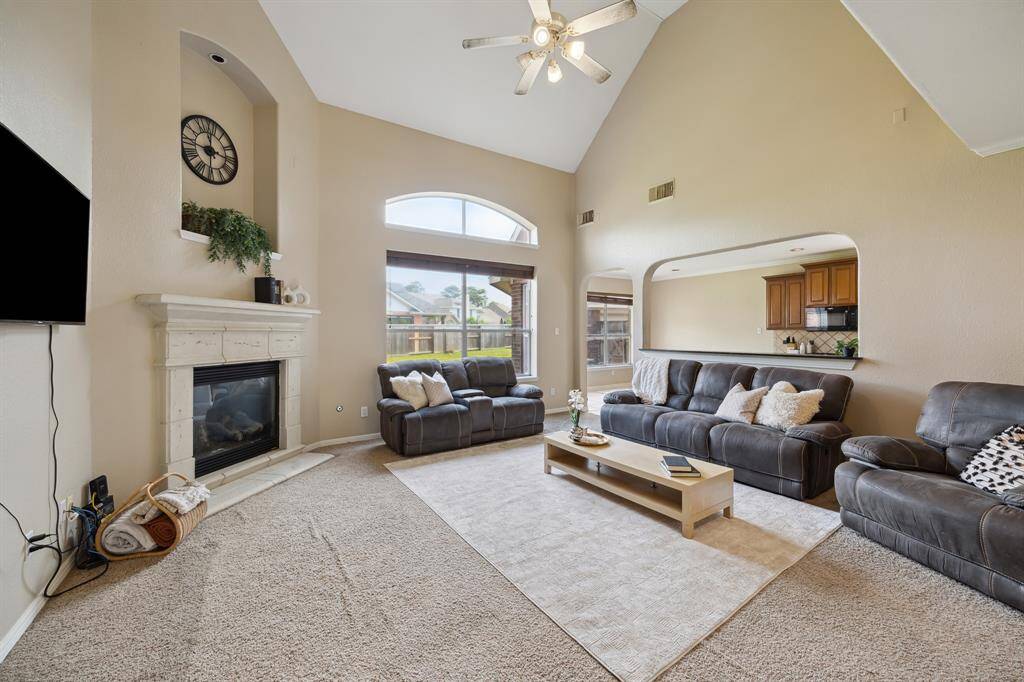 Bright and inviting kitchen with granite countertops, wood cabinetry, and a central island. The open layout connects to a dining area with large windows offering a view of the backyard, creating a perfect space for entertaining.