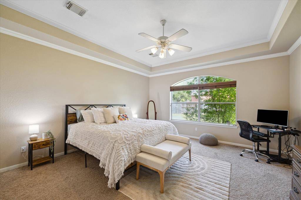 This inviting dining area features large windows for natural light, elegant wood flooring, and a stylish chandelier. It offers a seamless transition to adjacent spaces and includes tasteful wainscoting and an archway.
