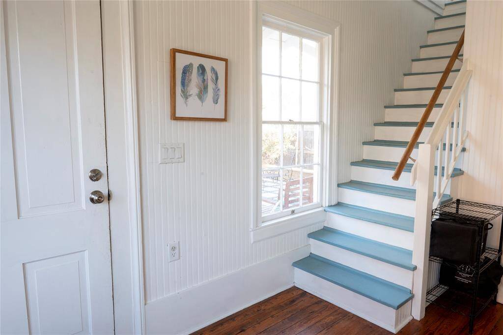 This bright entryway features a large window that lets in natural light. The area is decorated with a framed feather artwork and has wood flooring.