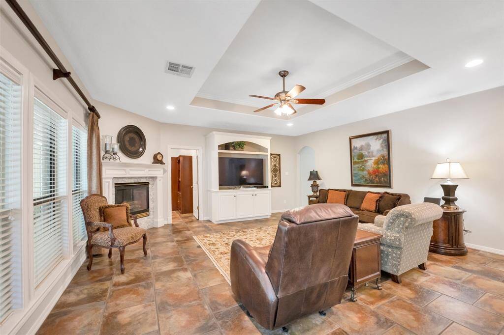 Tiled flooring, large windows, and a raised ceiling with fan make this room inviting and comfortable