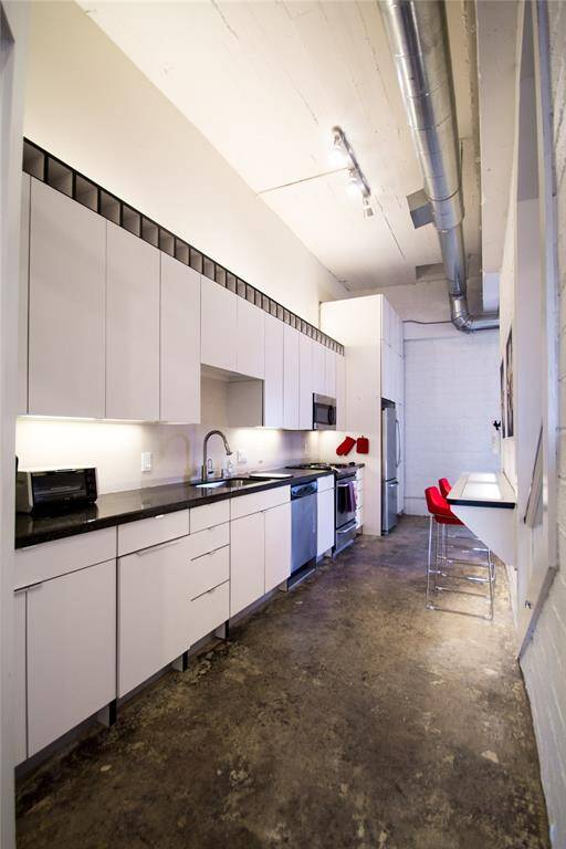 KITCHEN FEATURES STAINLESS APPLIANCES, WINE RACK, AND GRANITE COUNTERS.