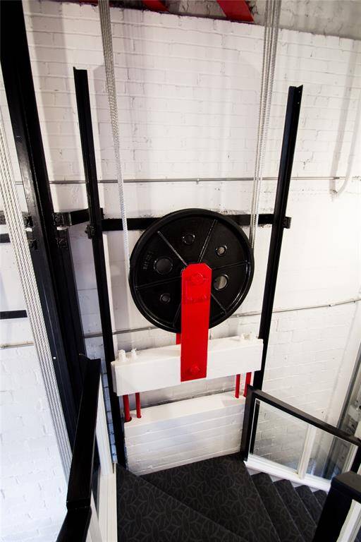 STAIRCASE IS INSIDE THE ORIGINAL FREIGHT ELEVATOR AS SEEN FROM THE PULLEYS AND CABLES.