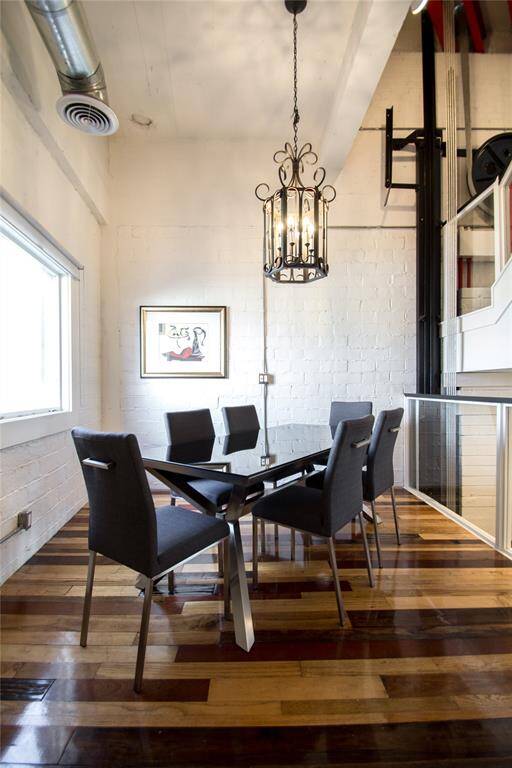 BREAKFAST ROOM WITH RECLAIMED WOOD FLOORING, METAL SPIRAL AC DUCTING, GLASS HAND RAILING OVERLOOKING STAIR CASE INSIDE THE ORIGINAL FREIGHT ELEVATOR SHAFT OF THE EARLY 1900'S BUILDING. WINDOW HAS AN EXCEPTIONAL VIEW OF DOWNTOWN HOUSTON.
