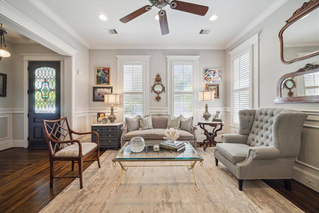 A refined welcome sets the tone at 1539 Rutland. Just off the entry, this formal living space blends timeless millwork, reclaimed hardwood floors, and tall, shuttered windows that flood the room with natural light. The leaded glass front door adds a bespoke touch of artistry. Elegant wainscoting, layered moldings, and classic ceiling details bring warmth and structure.