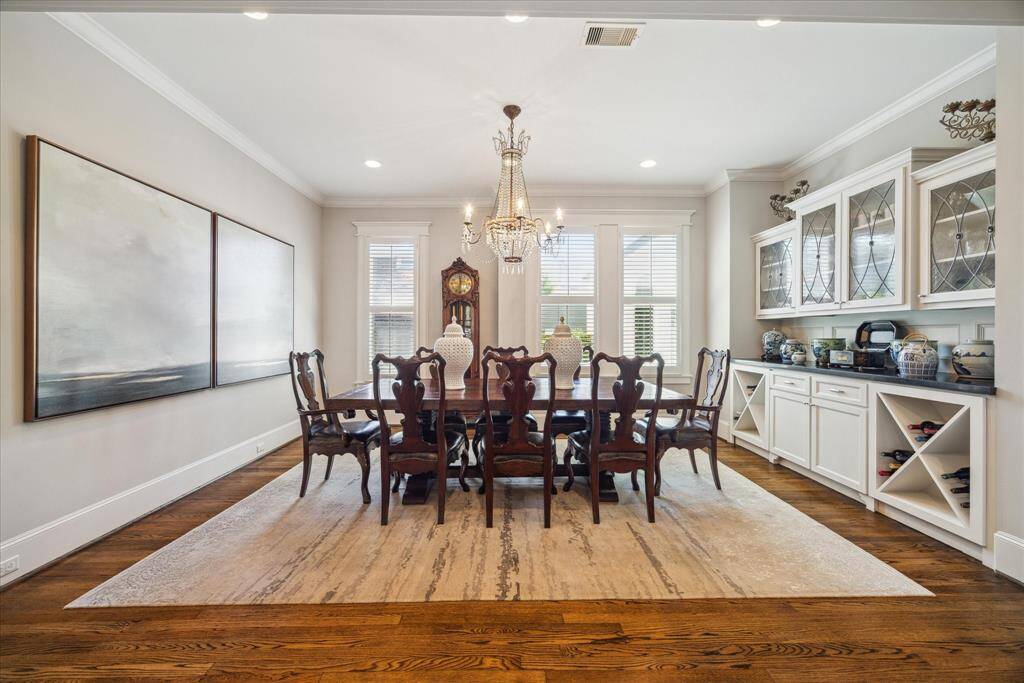 Elegant and inviting, the 16-foot-wide formal dining room is filled with natural light and classic design elements. Features include tall double-hung windows with custom trim, a statement crystal chandelier (included), and built-in glass-front cabinetry with wine storage.