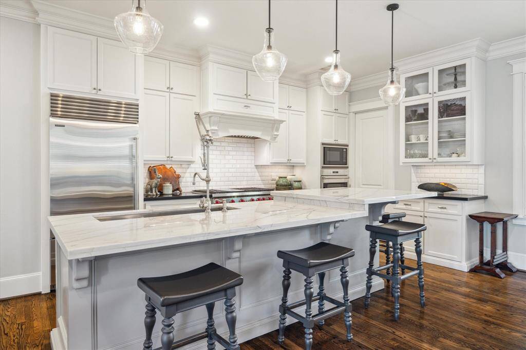 The heart of the home, this chef’s kitchen is a showpiece of form and function. Custom cabinetry, natural stone countertops,  SubZero built-in refrigerator , Wolf dual-oven range, convection wall oven, microwave, and satin nickel pull-down, crane style faucet are but a few of the amenities. A large center island invites casual gatherings with bar seating beneath trio pendant lights, while the built-in pantry and Bosch dishwasher add everyday practicality.