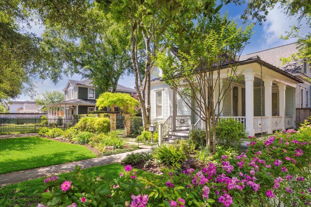 Viewed through a frame of seasonal plantings, this angle highlights the architectural grace and botanical layering that defines 1539 Rutland. The home’s classic Heights facade rises elegantly from a professionally landscaped setting by Moss. A brick-and-iron gate leads the eye toward the front path, while the porch swing and soft shadows hint at the slower pace.