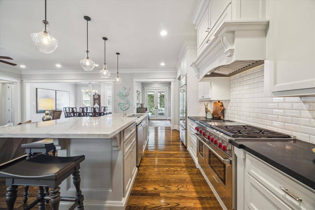 This vantage point captures the seamless circulation between culinary, dining, and living space. French doors at the rear lead to the outdoor living space, reinforcing the home's easy rhythm of indoor-outdoor entertaining. It’s the kind of kitchen that works as beautifully as it looks.