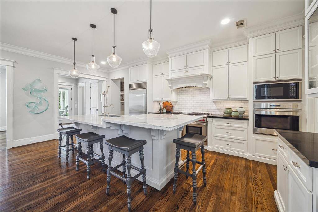At once classic and contemporary, this kitchen anchors the home with symmetry, scale, and style. The island doubles as a statement piece and social hub. Note the free-standing Wolf range in addition to wall ovens.