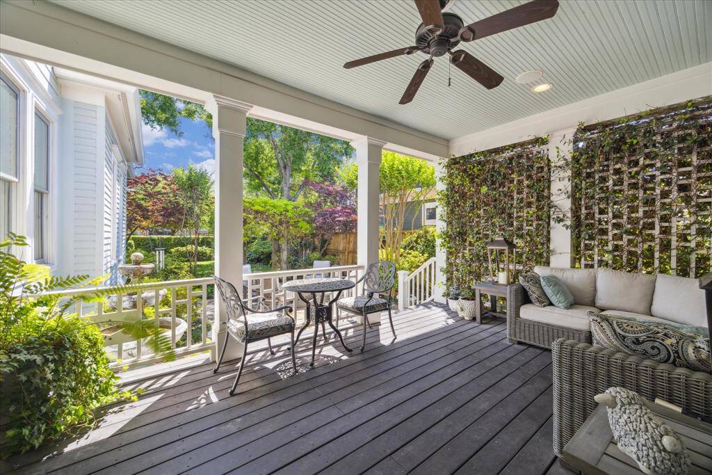This covered back porch feels like a secret garden retreat—wrapped in privacy lattice with climbing vines, a beadboard ceiling with a ceiling fan, and plenty of space to lounge or dine al fresco. Whether it’s coffee at sunrise or cocktails at dusk, the connection to the lush, professionally landscaped grounds makes this outdoor space an effortless extension of the home’s charm and character.
