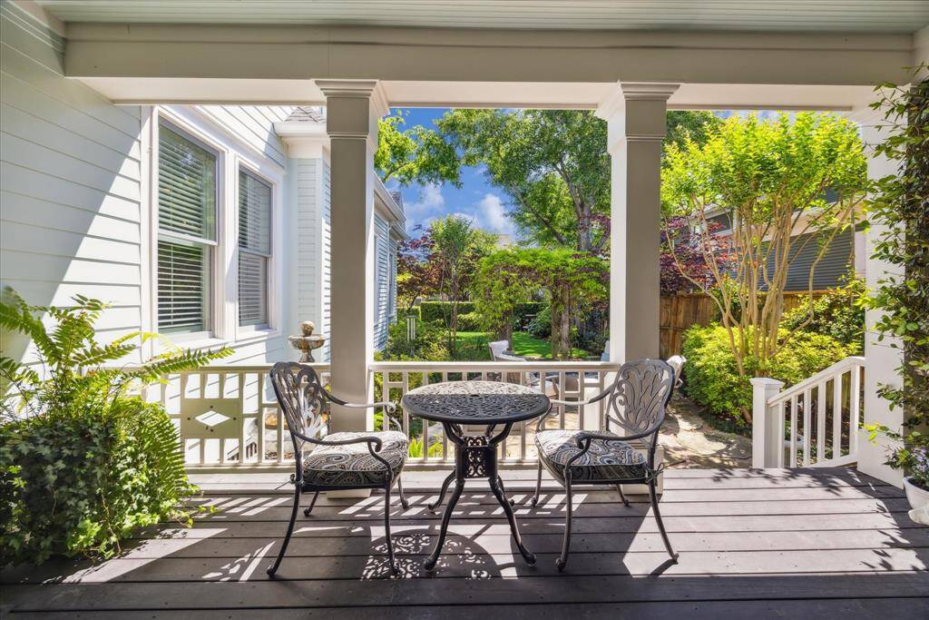 The covered porch overlooks the professionally landscaped yard and offers the ideal setting for morning coffee, evening cocktails, or simply taking in the view. With direct access to the garden and a line of sight to the vine-covered arbor, the space feels both connected and serene.