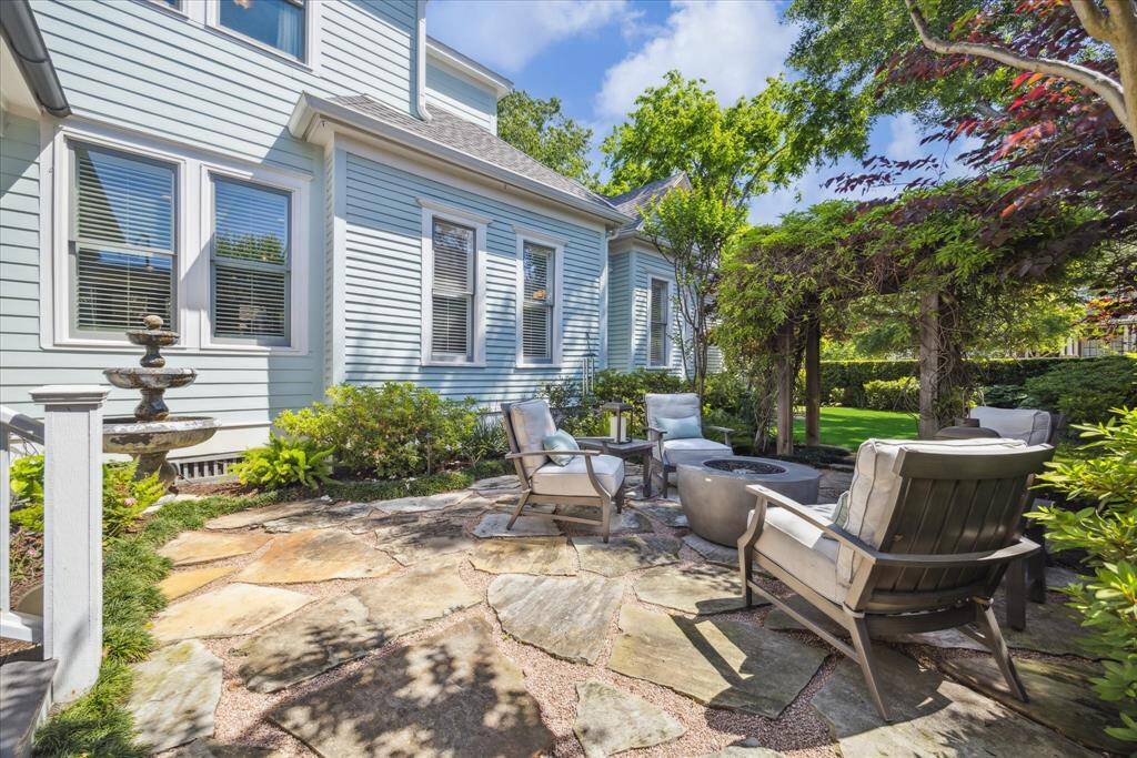This intimate flagstone patio invites you to unwind in style. Surrounded by lush greenery and anchored by a vine-wrapped arbor, the space blends structure and softness for a relaxed, elegant vibe. A classic tiered fountain adds a gentle soundtrack.
