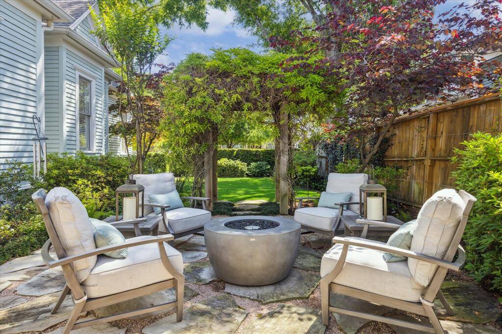 The backyard unfolds into a serene retreat designed by Moss Landscaping. Native yaupon, hollies, and crepe myrtles provide structure and privacy, while Redbuds and blooming azaleas layer in seasonal color. A tiered stone fountain adds a tranquil focal point, and flagstone paths lead to a patio space surrounded by soft liriope and boxwood hedges. This garden was designed to feel like a private escape in the heart of the Heights.