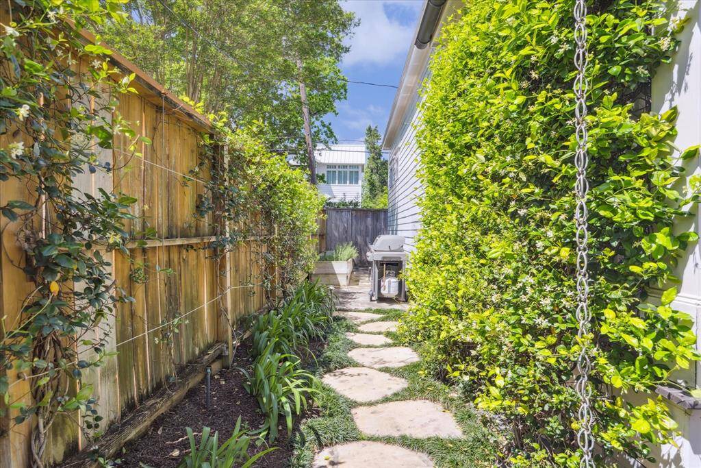 A winding flagstone path leads you through a lush, trellised corridor lined with blooming jasmine, structured greenery, and a custom-built raised planter box for herbs or seasonal vegetables. The space is equal parts functional and beauty and provides a space for grilling or composting all away from sight of the main house.