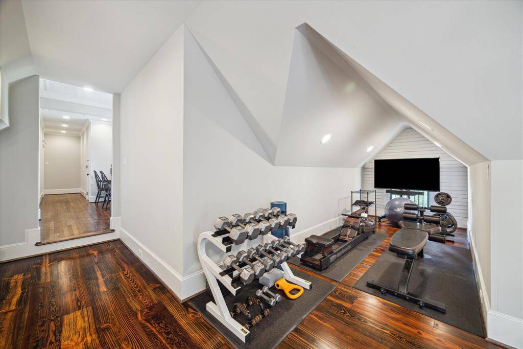 Carved beneath a dramatic pitched ceiling, this nook is currently utilized as a home gym.  With wood floors underfoot and custom shiplap detailing at the far wall, the space feels elevated.