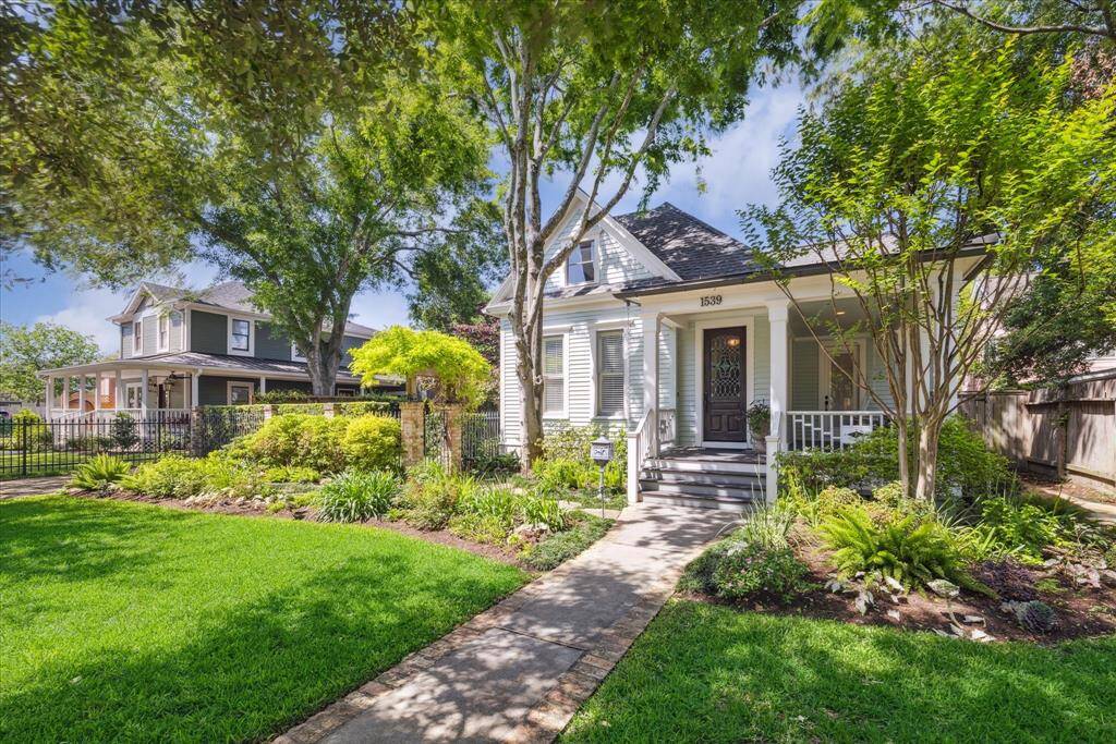The wrap-around porch, with wood columns and historically accurate trim, grounds the entry.   Every fern, flowering bed, and sculpted hedge reinforces the home’s timeless elegance and natural grace. A neighbor’s historic home adds context to the block—this isn’t just a house, it’s part of the architectural fabric of the Heights.