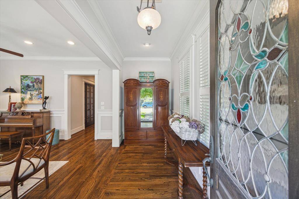 Framed by the intricate leaded glass of the original front door, the entry hall offers a graceful transition into the heart of the home. Reclaimed oak floors extend throughout the first floor, complemented by wide baseboards, detailed millwork, and classic crown molding that speaks to the home’s architectural integrity. Natural light filters through plantation shutters.