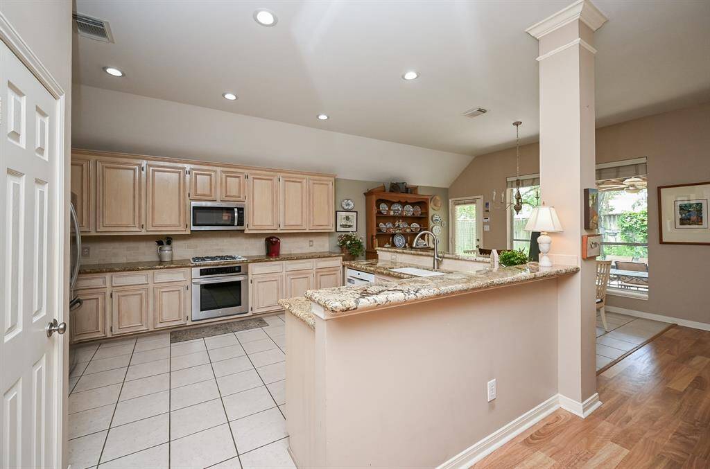 This spacious kitchen is the heart of the home, showcasing custom light-toned cabinetry & granite countertops, a built-in gas cooktop. A raised breakfast bar offers extra prep space and seamless flow to the dining and living areas.
