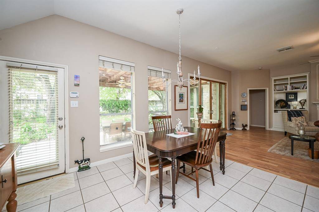The sunny breakfast nook is surrounded by large windows overlooking the backyard and covered patio.
