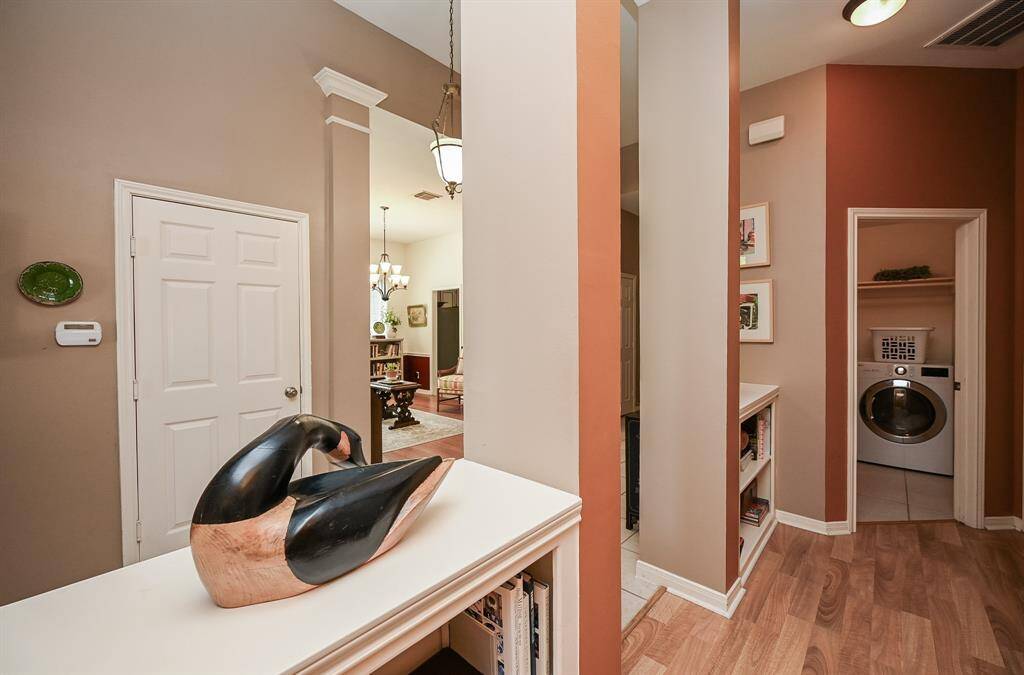 Transitional hallway featuring built-in shelving and access to the interior laundry room, with views of adjacent living spaces.