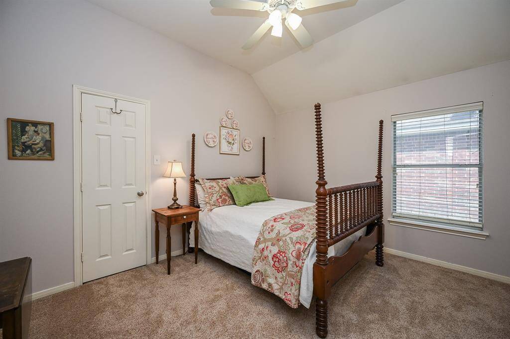 Comfortable secondary bedroom with high ceilings, neutral tones, and a large window providing natural light.
