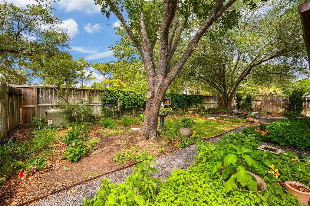 A beautifully maintained garden space with mature trees, planting beds, and a serene atmosphere perfect for outdoor enjoyment.