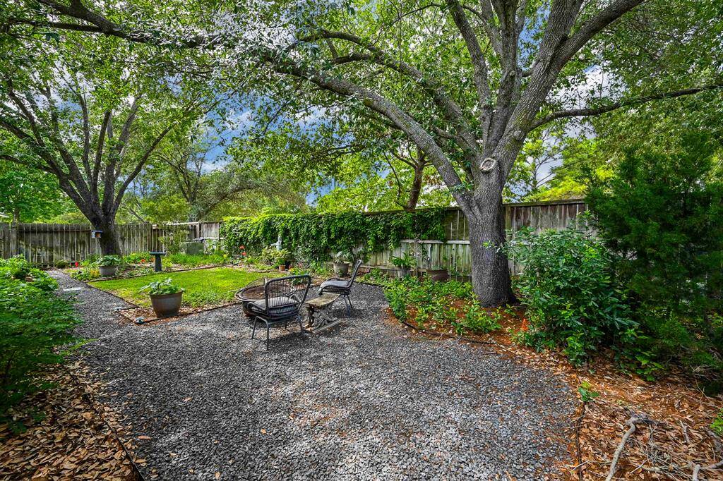 Shaded by towering trees, this inviting backyard seating area is ideal for relaxing in a tranquil natural setting.