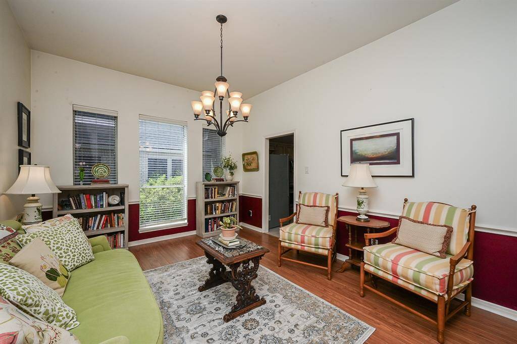 Cozy front room with large windows, high ceilings, and laminate wood flooring—perfect as a formal living area or home library.