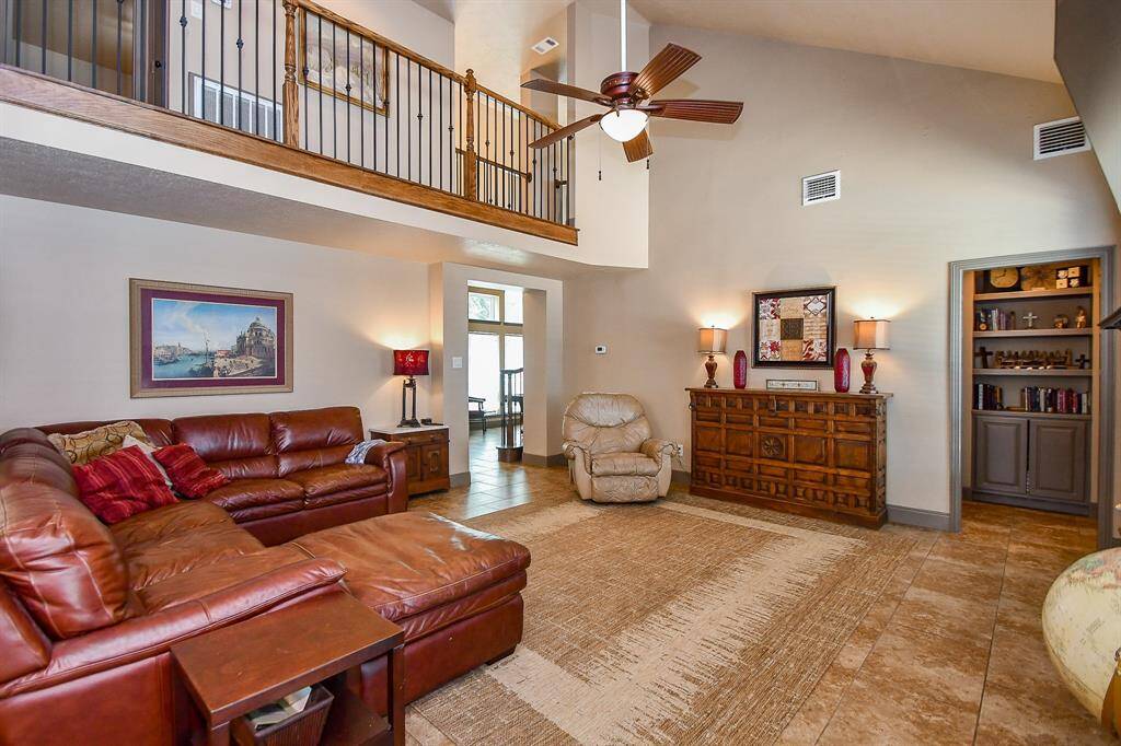 This spacious family room features high ceilings and an open second-floor balcony. Offering plenty of room for family and friends.  Abundant natural light enhances the warm, inviting atmosphere.