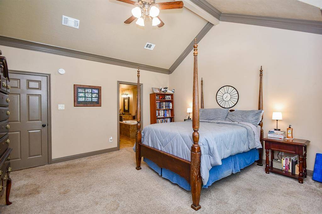 This spacious bedroom features a high vaulted ceiling, a wall of windows with an ensuite bathroom.