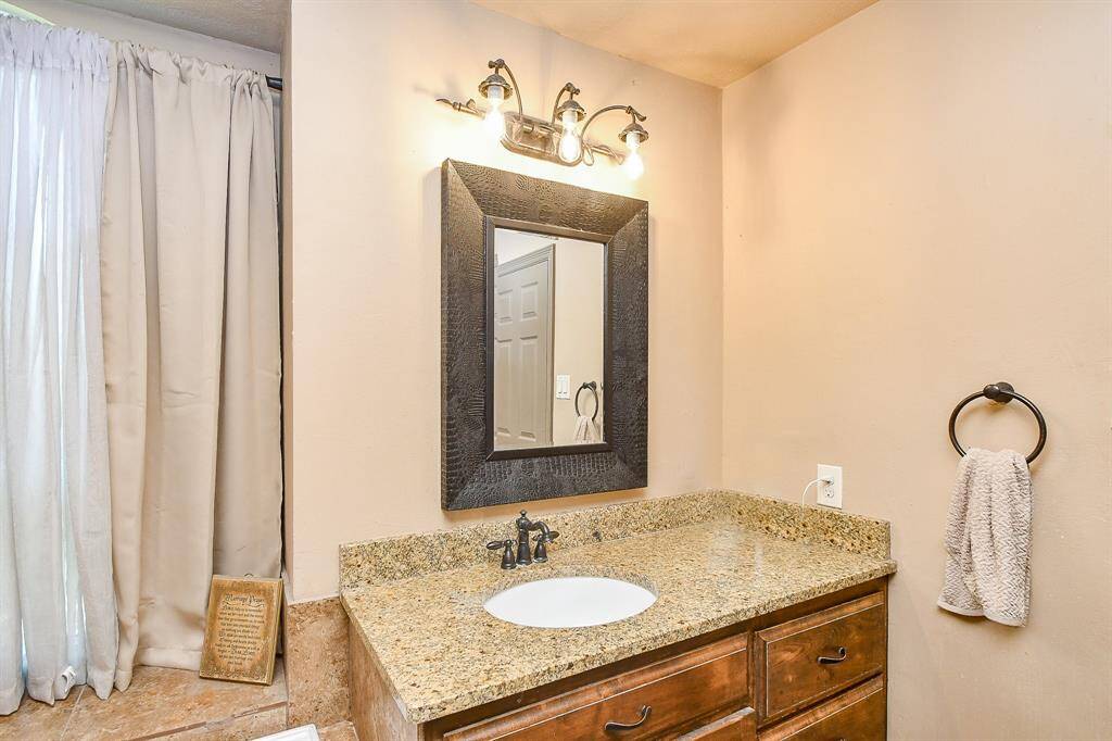 This area of the primary bathroom features a granite countertop with a built-in sink.