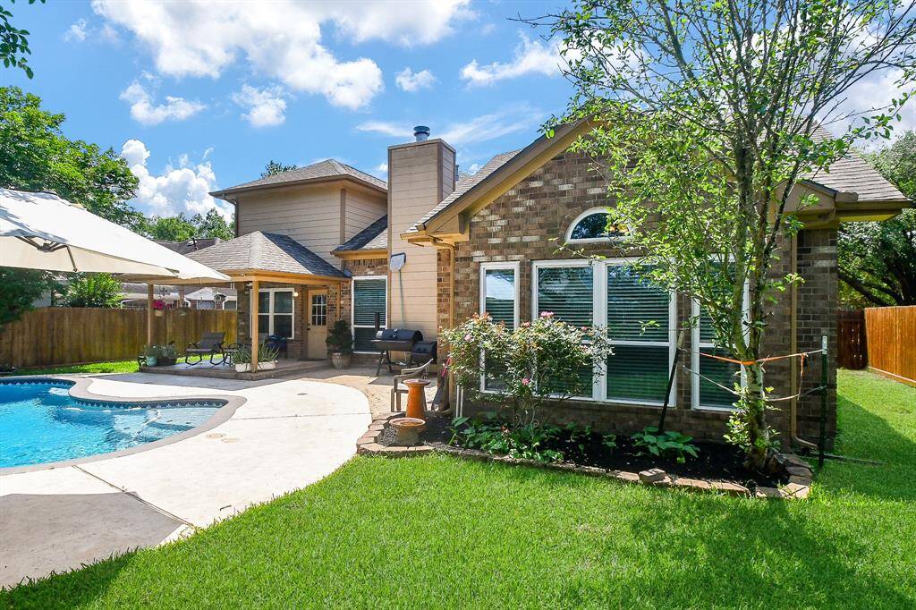 This charming home features a beautifully landscaped backyard with a pool, patio area, and lush greenery. It offers a perfect outdoor space for relaxation and entertainment.