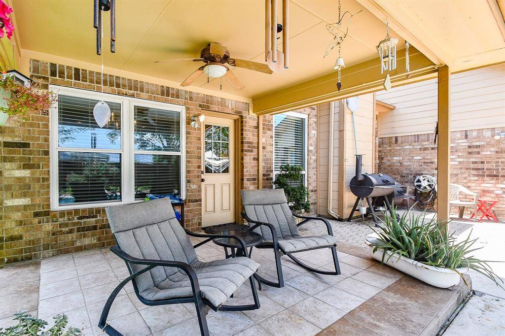 Charming covered patio featuring ceiling fan. Ideal for relaxation and entertaining, with a view of the inviting pool.