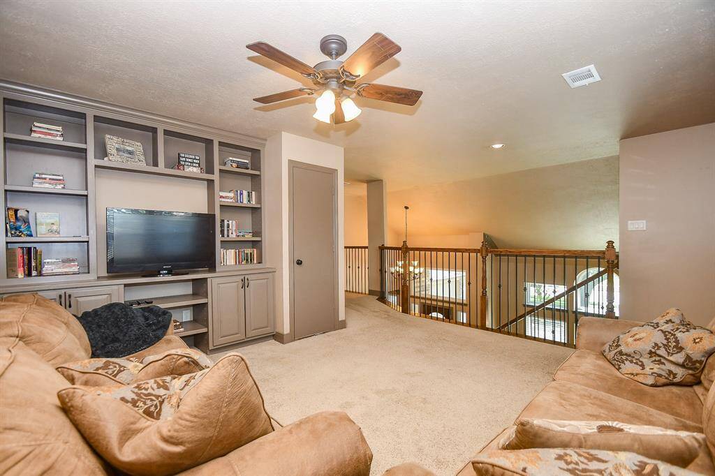This spacious game room area offers a built-in entertainment center with shelving. It overlooks the lower level, creating an open, airy feel perfect for relaxation or entertainment.