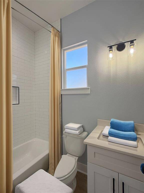 A beautifully upscale bathroom featuring a modern subway tile shower  with black fixtures, and bright natural light streaming through the window for a fresh and inviting ambiance. Staged