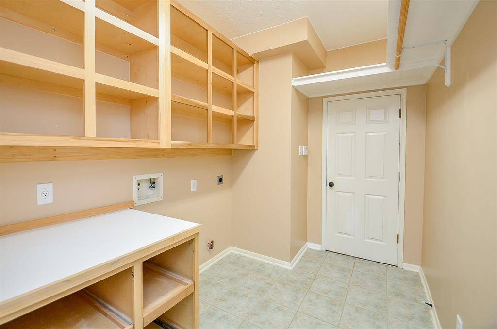 Spacious Laundry Room with Custom Built Ins for Storage and Handy Folding Table.