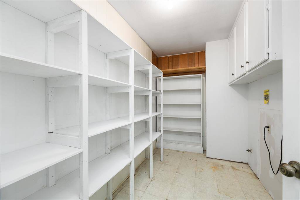 The expansive pantry and laundry room offers abundant storage with multiple white shelves and cabinets, keeping everything organized and within reach.