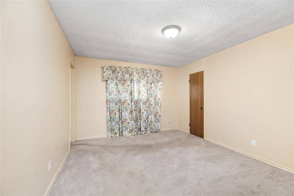 This secondary bedroom offers a cozy and versatile space with soft, neutral-color walls and plush carpeting. Perfect for a bedroom or home office, it provides a comfortable and inviting atmosphere.