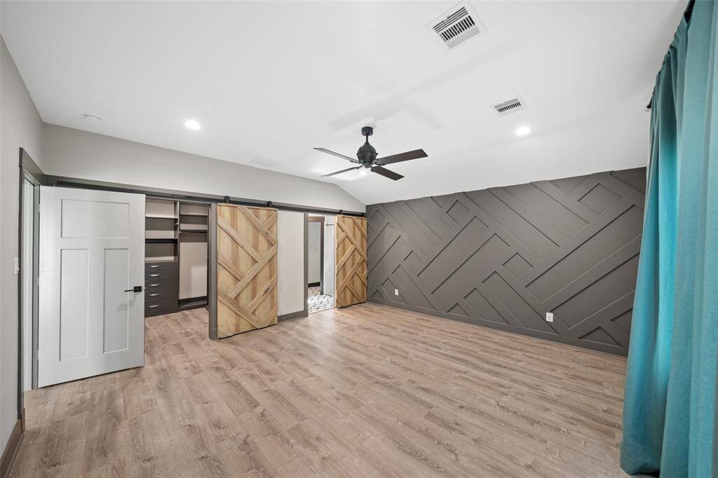 The primary suite is towards the back of the home and features a stylish accent wall and matching barn-style doors to the primary closet and en-suite bath.