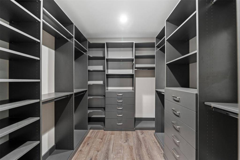 Behind a sliding barn door is the primary closet. Ample space with custom shelving, racks and drawers.