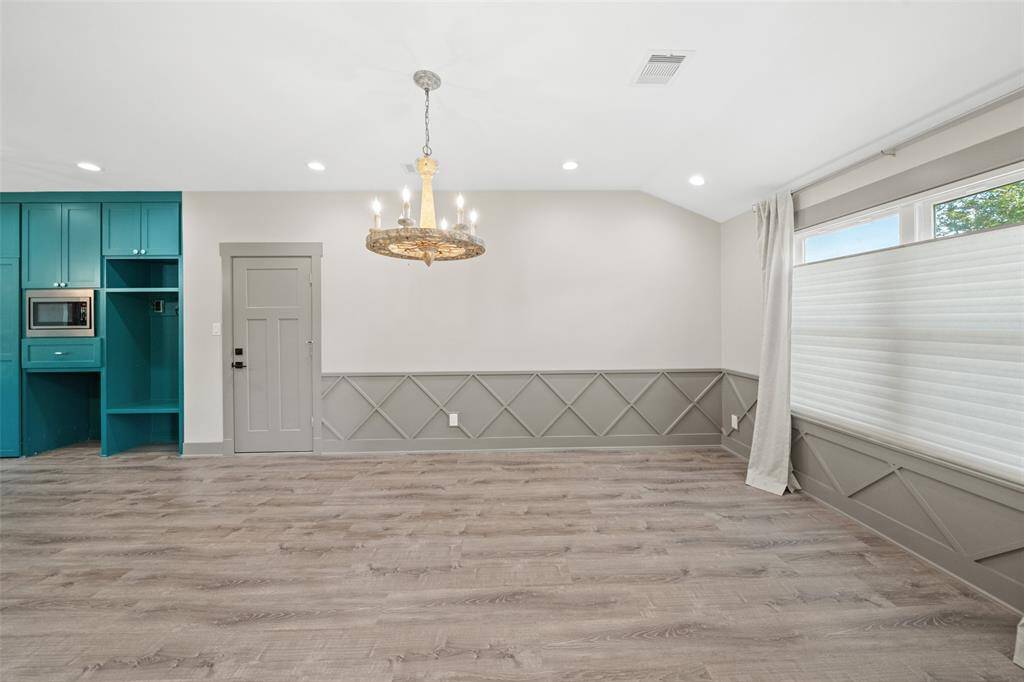 The dining room is adorned with a beautiful light fixture and has views into the manicured front yard.