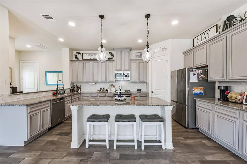 Chef's eat-in island kitchen features an abundance of cabinets, lengthy granite countertops and stainless steel appliances